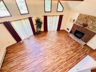 2383 Eagle Path, Bushkill, PA 18324 - living area featuring high vaulted ceiling, healthy amount of natural light, a fireplace, and wood finished floors