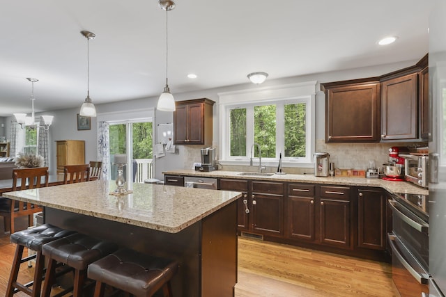 1127 Fillmore St, East Stroudsburg, PA 18301 - kitchen with appliances with stainless steel finishes, light wood-style floors, light stone counters, a kitchen breakfast bar, and decorative backsplash