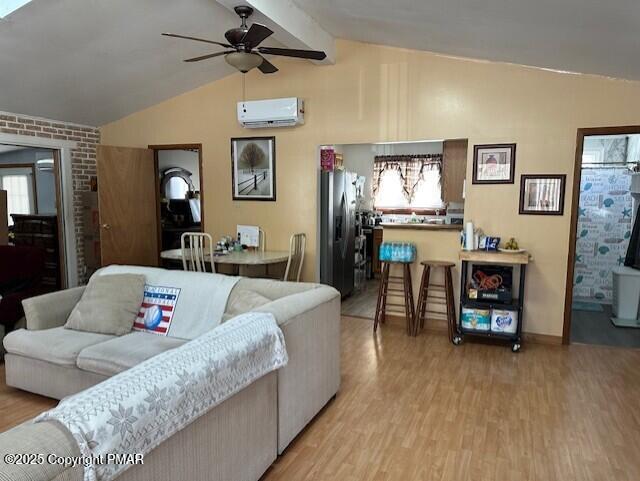 living room with vaulted ceiling with beams, a wall mounted air conditioner, ceiling fan, and light hardwood / wood-style flooring