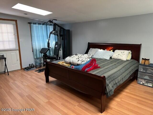 bedroom with a skylight and wood finished floors