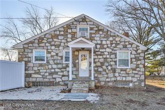 view of front of house with stone siding and fence