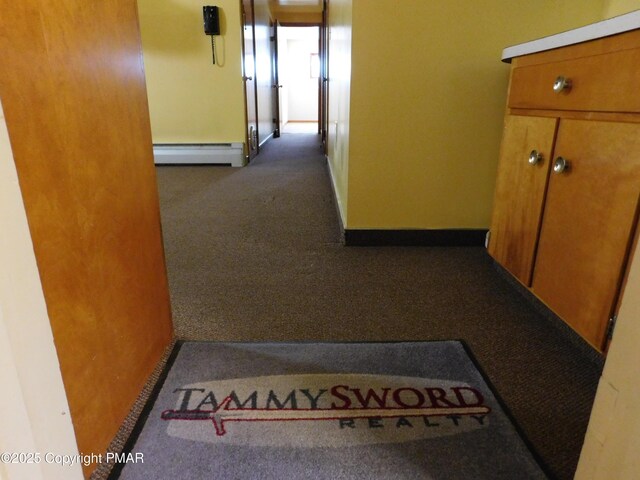 corridor featuring dark carpet and baseboard heating