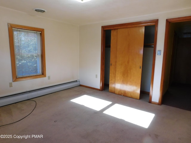 unfurnished bedroom featuring visible vents, a baseboard heating unit, a closet, carpet, and baseboards