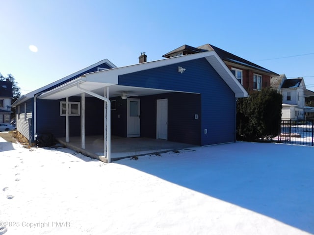 exterior space with fence, a chimney, ceiling fan, a carport, and a patio area