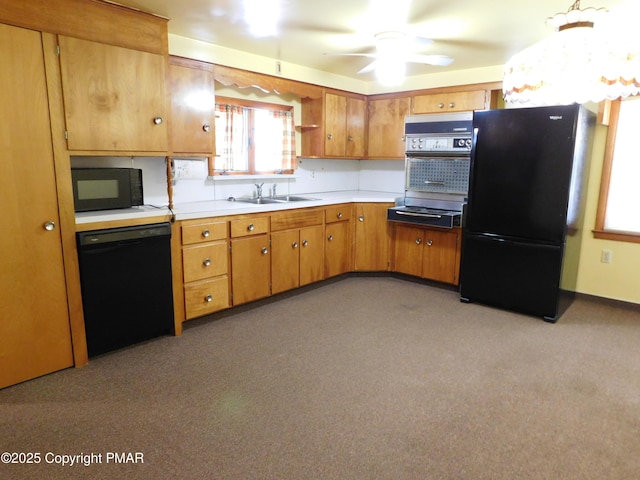 kitchen with light countertops, brown cabinetry, black appliances, a ceiling fan, and a sink