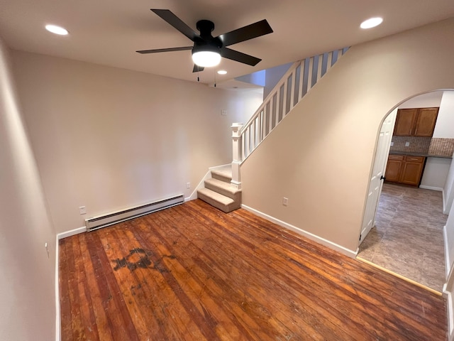 unfurnished room with baseboards, stairs, light wood-type flooring, arched walkways, and a baseboard radiator