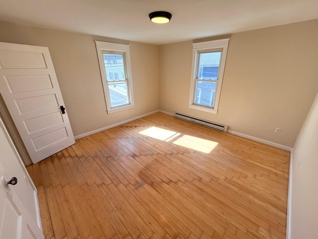 unfurnished room with baseboards, baseboard heating, and light wood finished floors