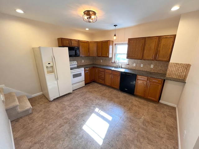 kitchen with dark countertops, backsplash, brown cabinets, black appliances, and a sink