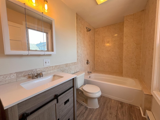 bathroom with tile walls, toilet, bathtub / shower combination, wood finished floors, and vanity