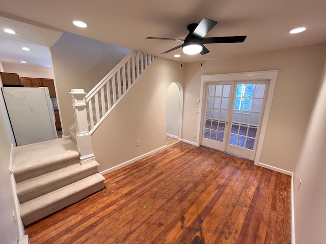 interior space featuring hardwood / wood-style floors, recessed lighting, arched walkways, baseboards, and stairs