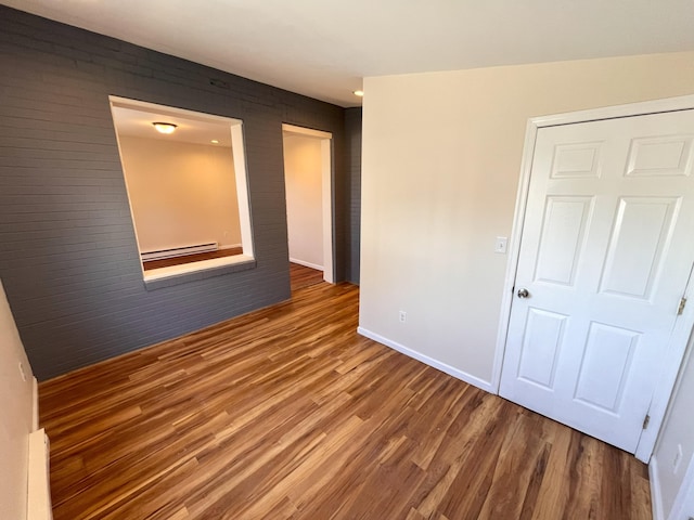 spare room featuring wood finished floors, baseboards, and baseboard heating