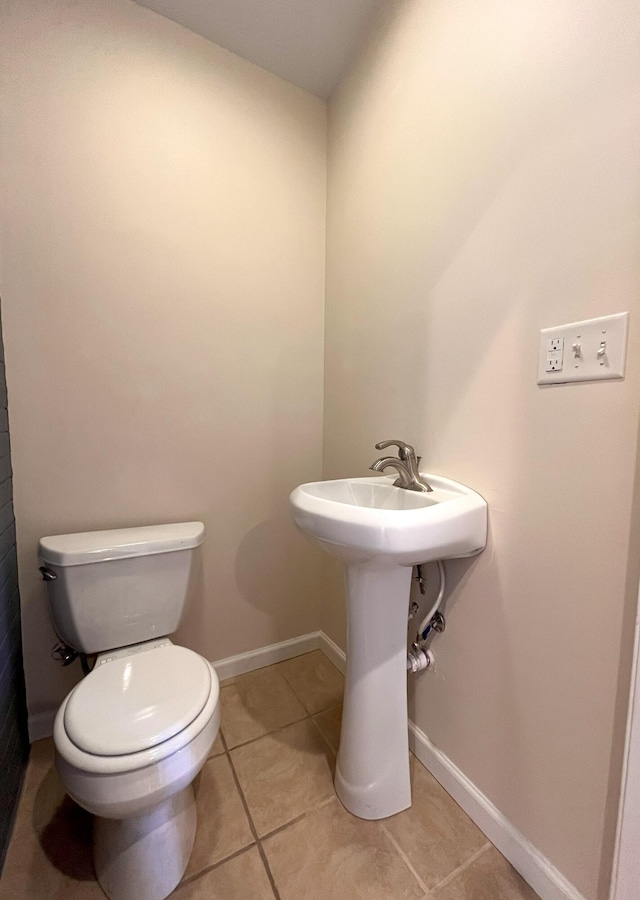 bathroom featuring tile patterned floors, baseboards, and toilet