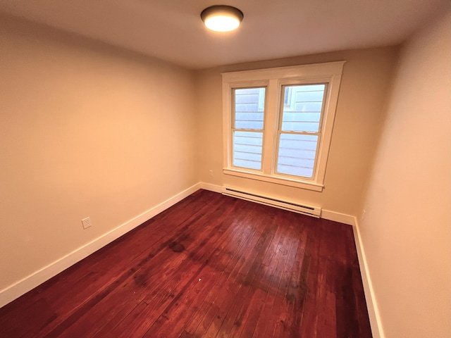 unfurnished room featuring a baseboard heating unit, baseboards, and dark wood finished floors