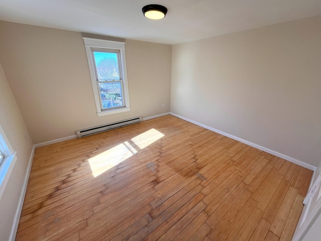 spare room with light wood-style flooring, baseboards, and a baseboard radiator