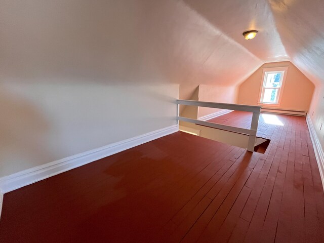 additional living space featuring vaulted ceiling, a baseboard radiator, baseboards, and wood-type flooring