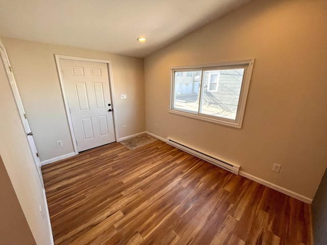 interior space with baseboards, baseboard heating, wood finished floors, and vaulted ceiling