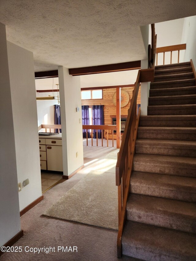 stairs featuring a textured ceiling and carpet flooring