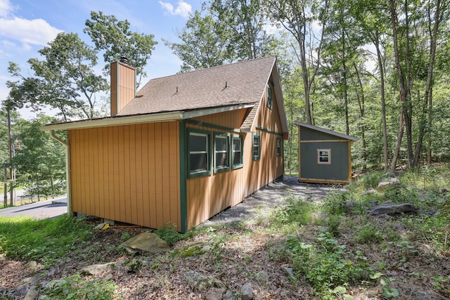 3109 Snowden Dr, Bushkill, PA 18324 - view of side of home with a chimney, a shingled roof, and a shed