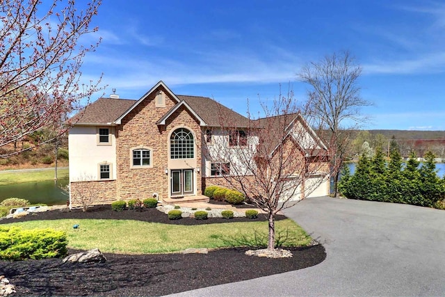 301 Reagan Dr, East Stroudsburg, PA 18301 - traditional-style house featuring a front lawn, stone siding, stucco siding, a water view, and driveway
