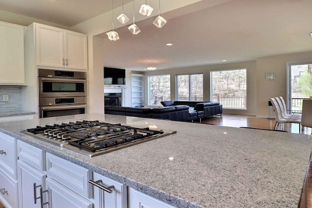 301 Reagan Dr, East Stroudsburg, PA 18301 - kitchen with white cabinets, open floor plan, appliances with stainless steel finishes, and light stone countertops