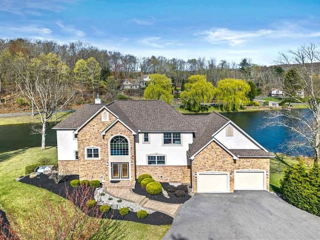 301 Reagan Dr, East Stroudsburg, PA 18301 - view of front of house with a garage, stucco siding, a shingled roof, a water view, and driveway