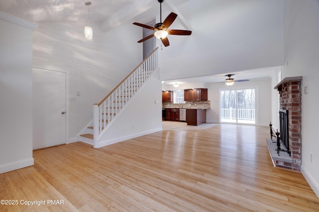 unfurnished living room featuring a fireplace, high vaulted ceiling, beamed ceiling, ceiling fan, and light hardwood / wood-style flooring