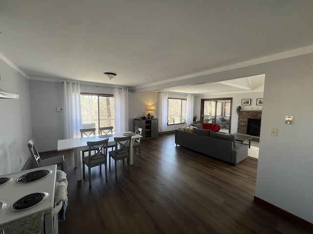 dining area featuring ornamental molding, dark wood-style flooring, a brick fireplace, and a wealth of natural light