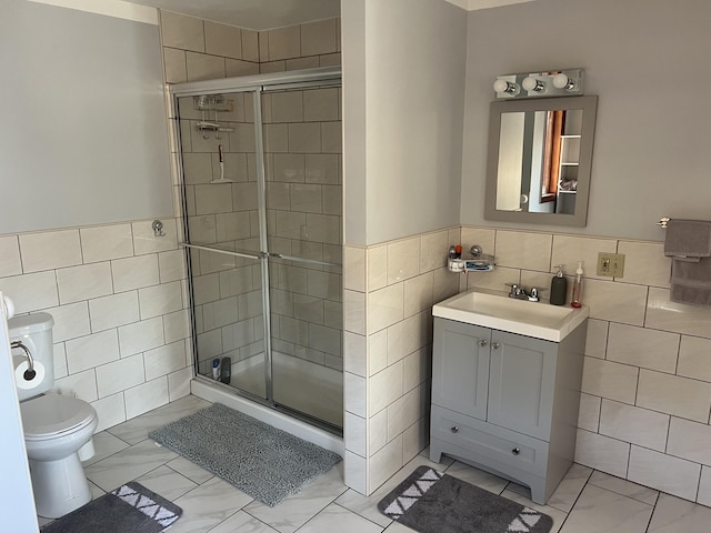 full bath with marble finish floor, a shower stall, and tile walls