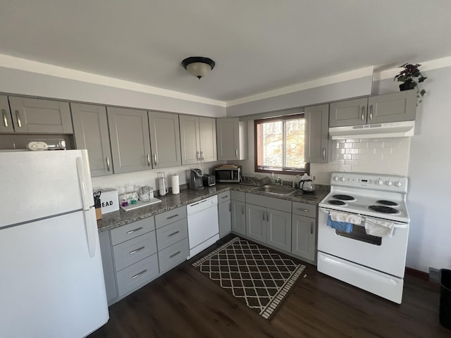 kitchen with white appliances, dark wood-style floors, gray cabinets, under cabinet range hood, and a sink