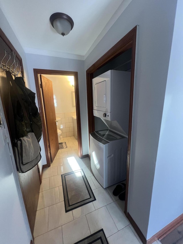 washroom with stacked washer and dryer, laundry area, and light tile patterned floors