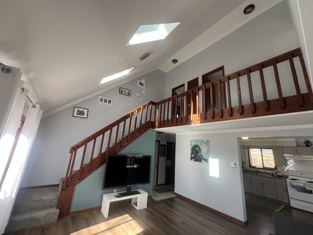 living room featuring high vaulted ceiling, a skylight, stairway, and wood finished floors