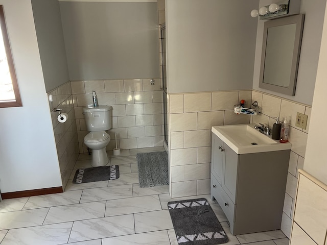 full bathroom featuring marble finish floor, tile walls, toilet, a shower with shower door, and vanity