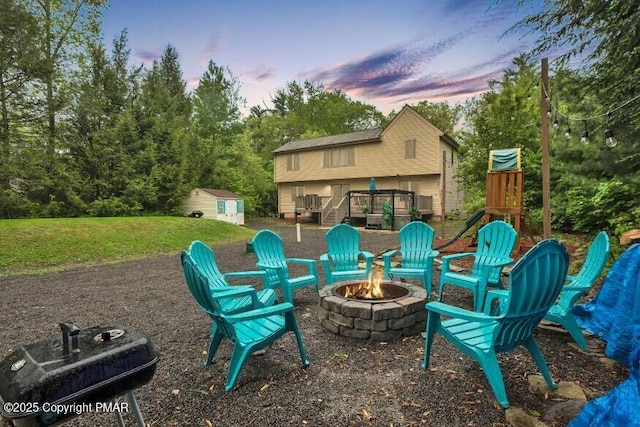 view of patio with a deck, an outbuilding, a storage shed, and an outdoor fire pit