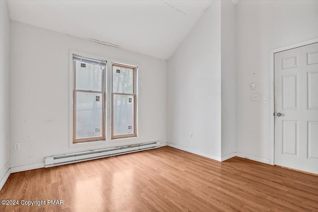 empty room with baseboards, vaulted ceiling, light wood finished floors, and baseboard heating