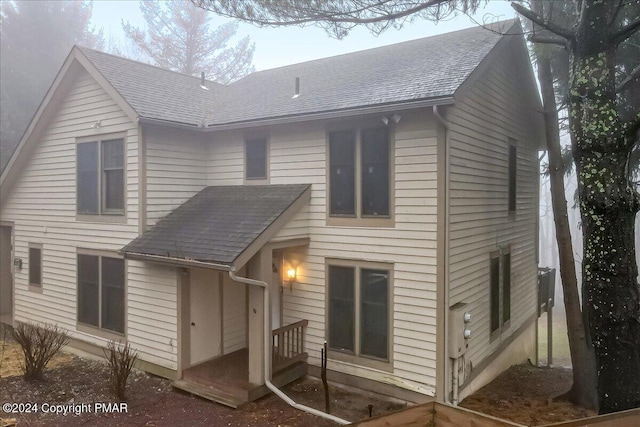 rear view of property featuring roof with shingles