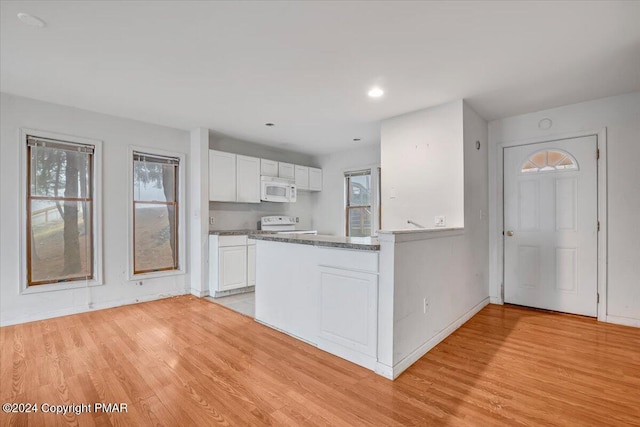 kitchen featuring a healthy amount of sunlight, white microwave, white cabinets, and light wood-style floors