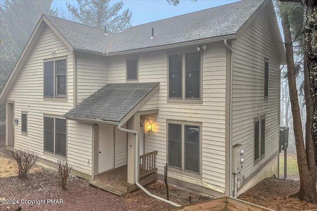 rear view of house with a shingled roof