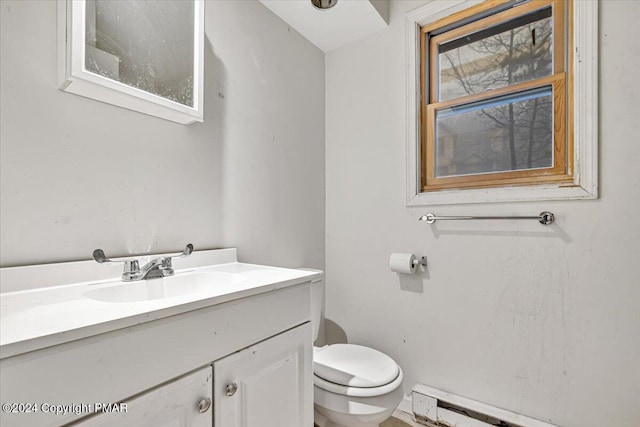 bathroom with toilet, plenty of natural light, a baseboard heating unit, and vanity