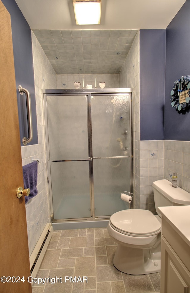 full bathroom featuring tile walls, toilet, a baseboard heating unit, a stall shower, and vanity