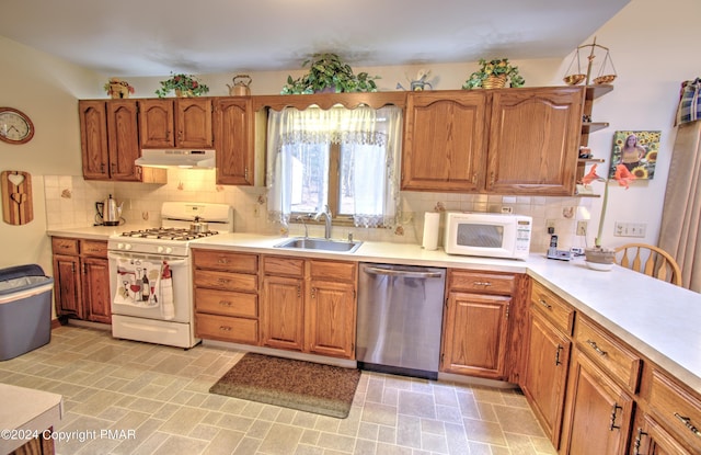 kitchen featuring under cabinet range hood, white appliances, a sink, light countertops, and decorative backsplash