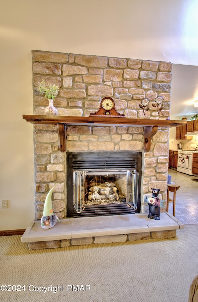 room details with carpet, a stone fireplace, white gas range, and under cabinet range hood