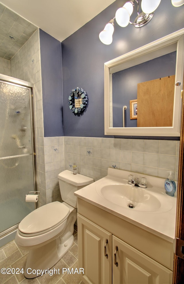 full bathroom featuring tile walls, toilet, vanity, a shower stall, and tile patterned floors