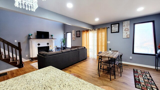 8237 Natures Dr, Tobyhanna, PA 18466 - living area with a fireplace with raised hearth, wood finished floors, recessed lighting, baseboards, and stairs
