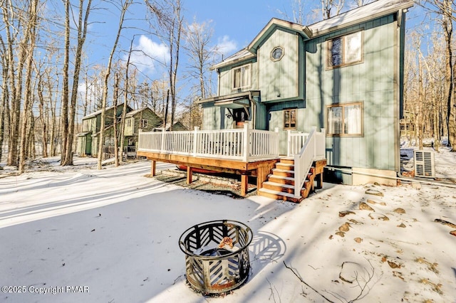 snow covered back of property featuring an outdoor fire pit and a deck