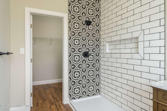 bathroom featuring hardwood / wood-style flooring, vanity, and a tile shower