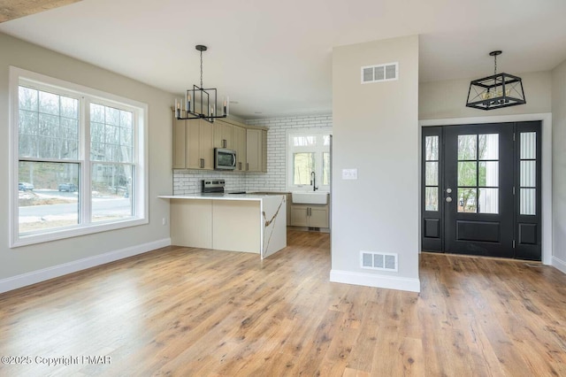 kitchen with appliances with stainless steel finishes, light hardwood / wood-style floors, sink, and hanging light fixtures