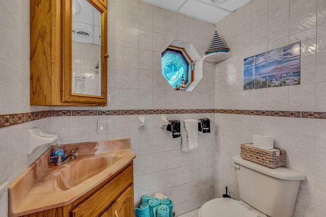 bathroom with toilet, tile walls, and vanity