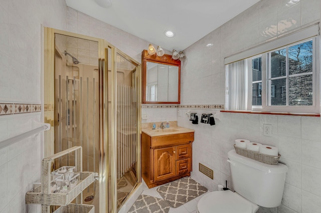 bathroom with tile walls, toilet, a shower stall, vanity, and tile patterned floors