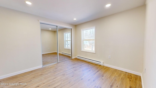 unfurnished bedroom featuring light wood finished floors, baseboards, baseboard heating, and recessed lighting