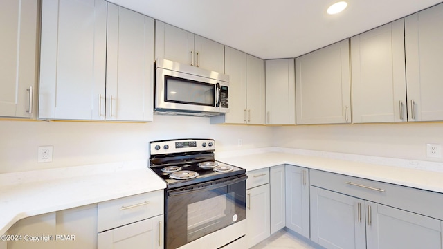 kitchen with recessed lighting, gray cabinetry, electric range, light countertops, and stainless steel microwave